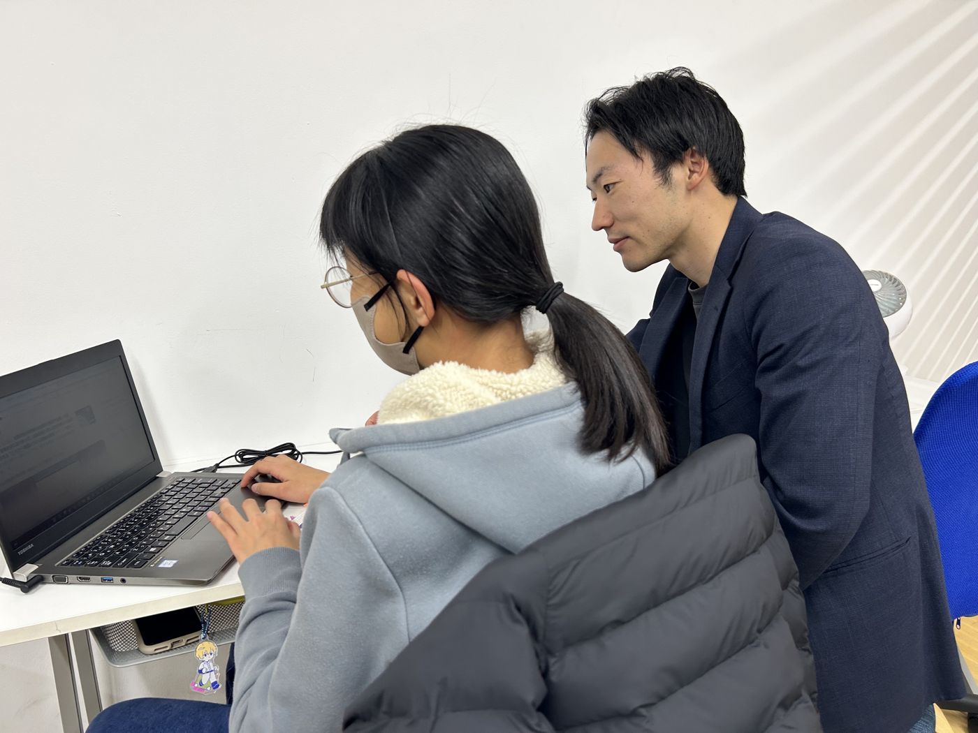 コーチが生徒の横について、学習の進み具合を一緒に確かめている様子