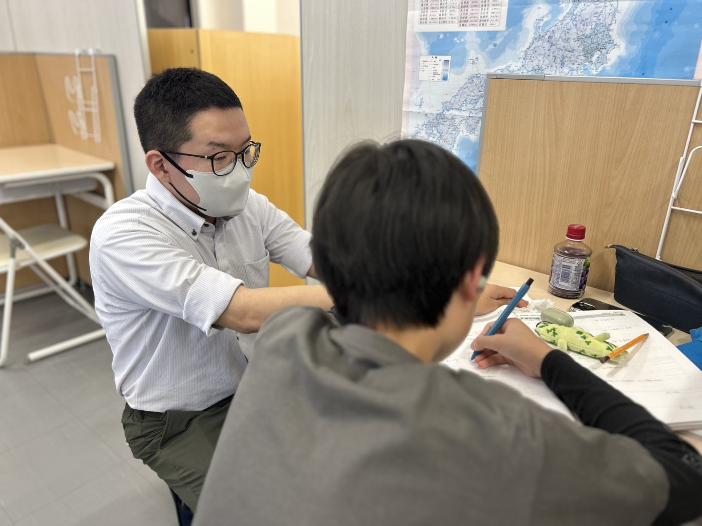 日向校の谷が生徒の横について、学習の進み具合を一緒に確かめている様子